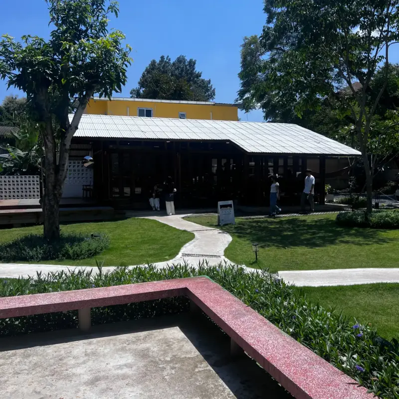 Long wooden façade facing a garden with a curved path
