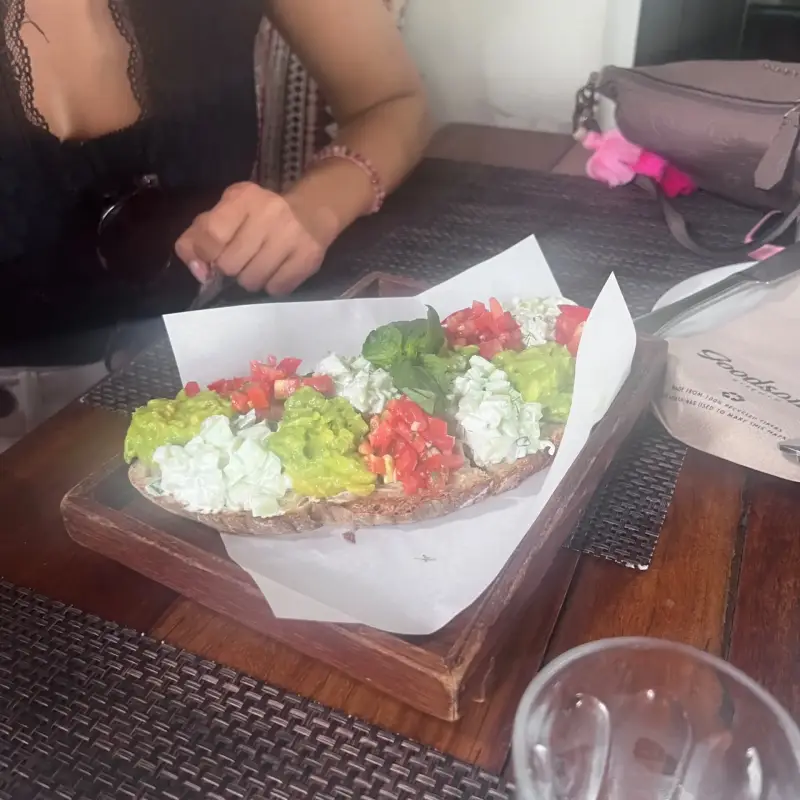 Belegtes Brot mit grünem und hellem Belag sowie Tomatenstücken