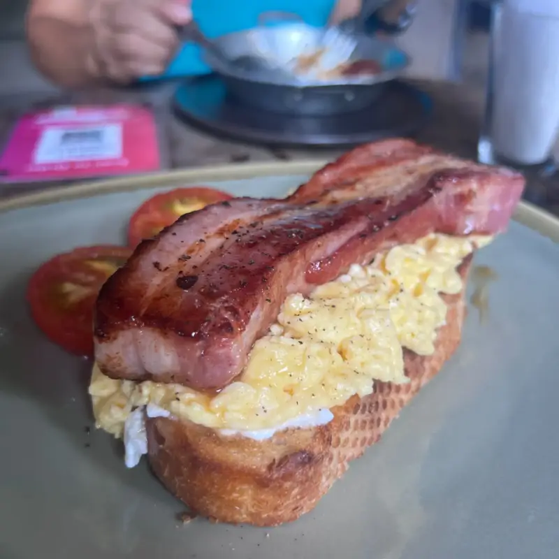 Dickes Toastbrot mit Rührei und gebratenen Speckstreifen