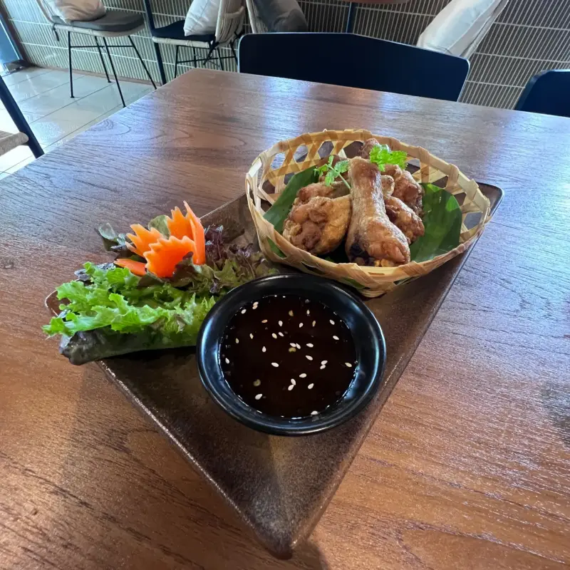 Korb mit frittierten Häppchen, Salat und einer Schale dunkler Sauce