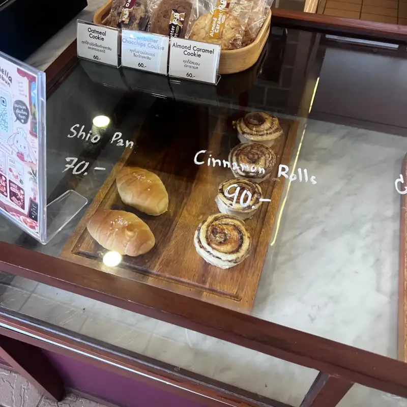 Brötchen und Zimtschnecken unter einer beschrifteten Glasabdeckung