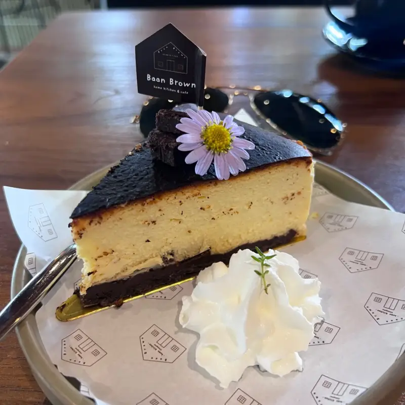 Helles Kuchenstück mit dunkler Oberfläche, Blüte und Sahne