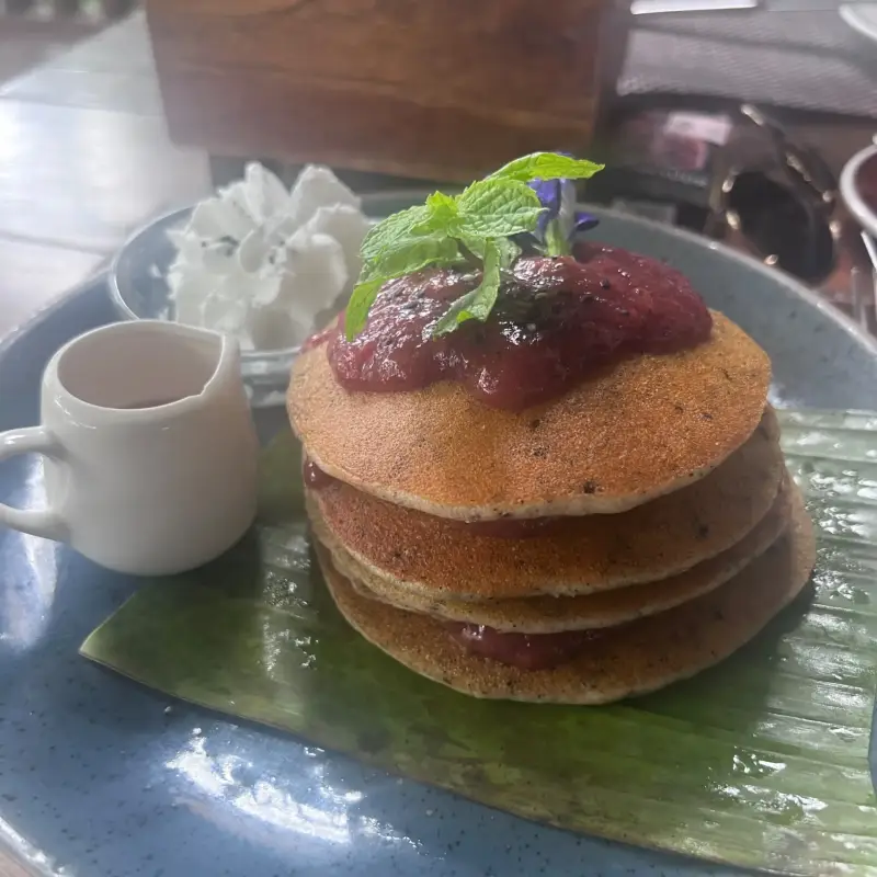 Gestapelte Pancakes mit Fruchtbelag, Minze und einem kleinen Kännchen