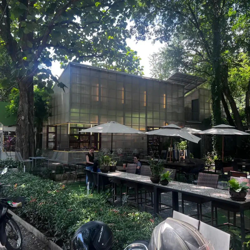 Cafégebäude hinter Gartensitzplätzen und großen Sonnenschirmen