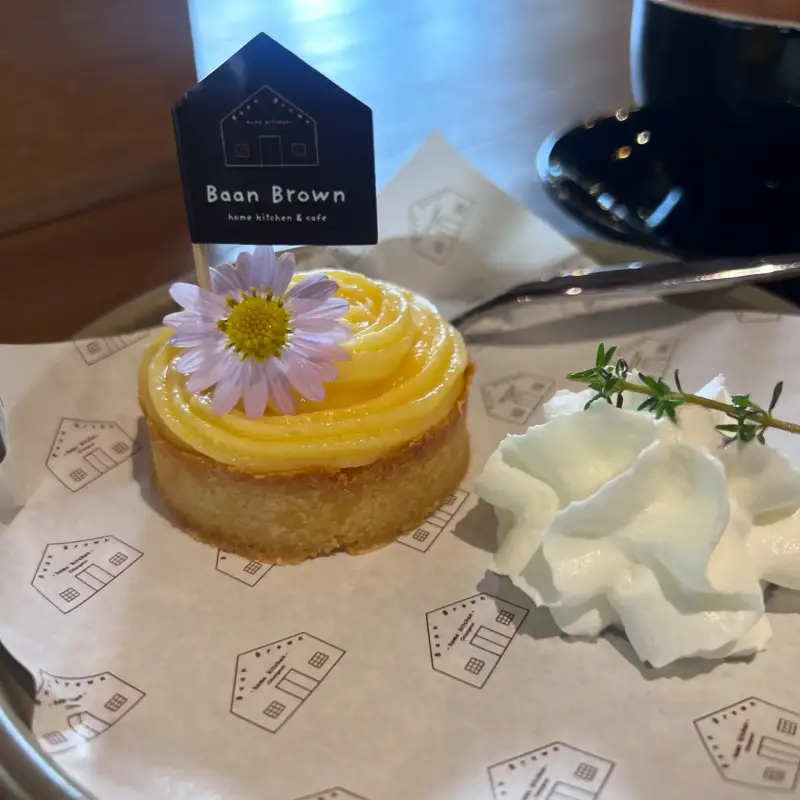Kleines Törtchen mit gelber Creme, Blütendekoration und Sahne