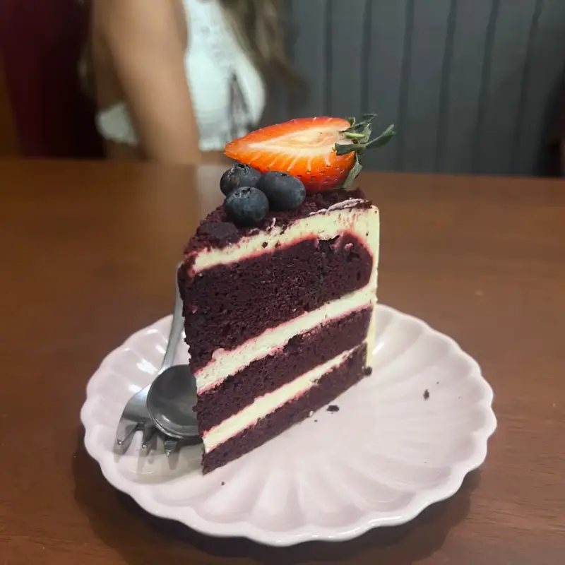 Dunkles Tortenstück mit hellen Cremeschichten und Beeren